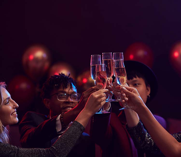 Group of elegant young people raising champagne glasses while enjoying party in nightclub.